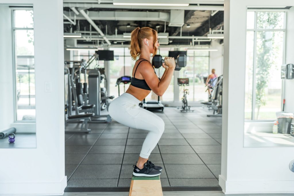 Woman working out in the gym with weights squatting. Weight loss. 