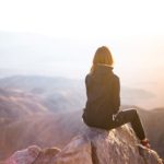 Woman sitting on top of mountain. Move past failure