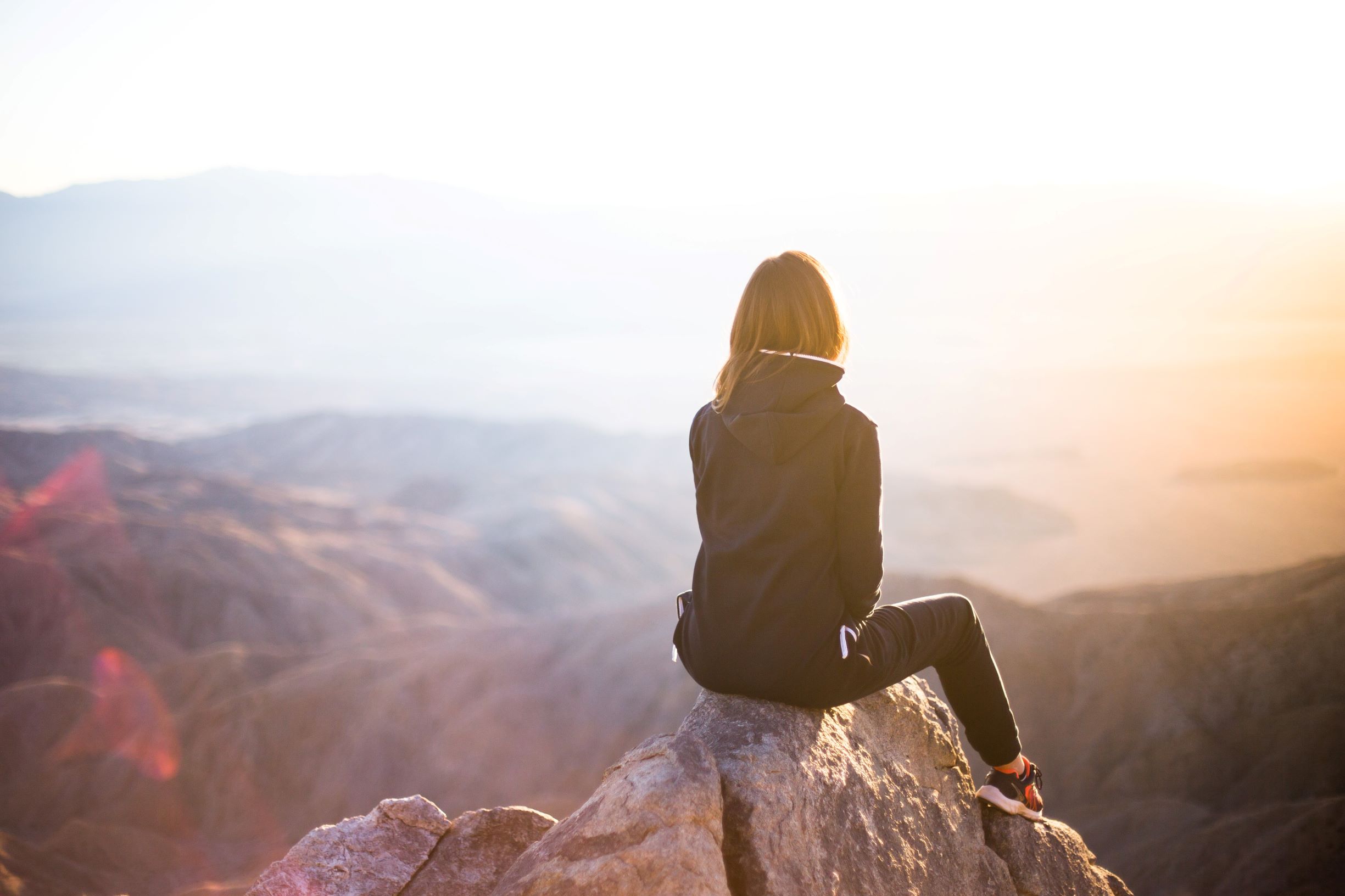Woman sitting on top of mountain. Move past failure