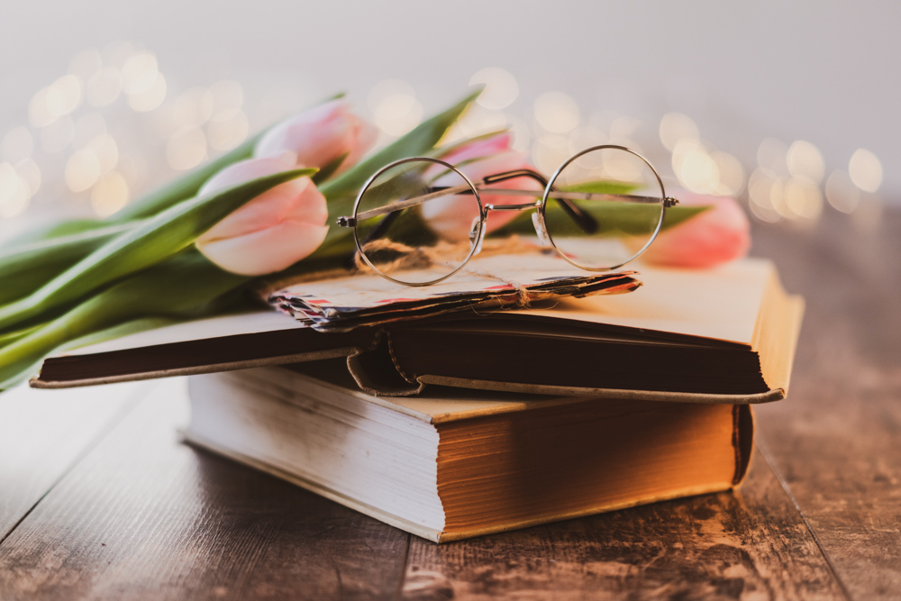eyeglasses on top of books with flowers