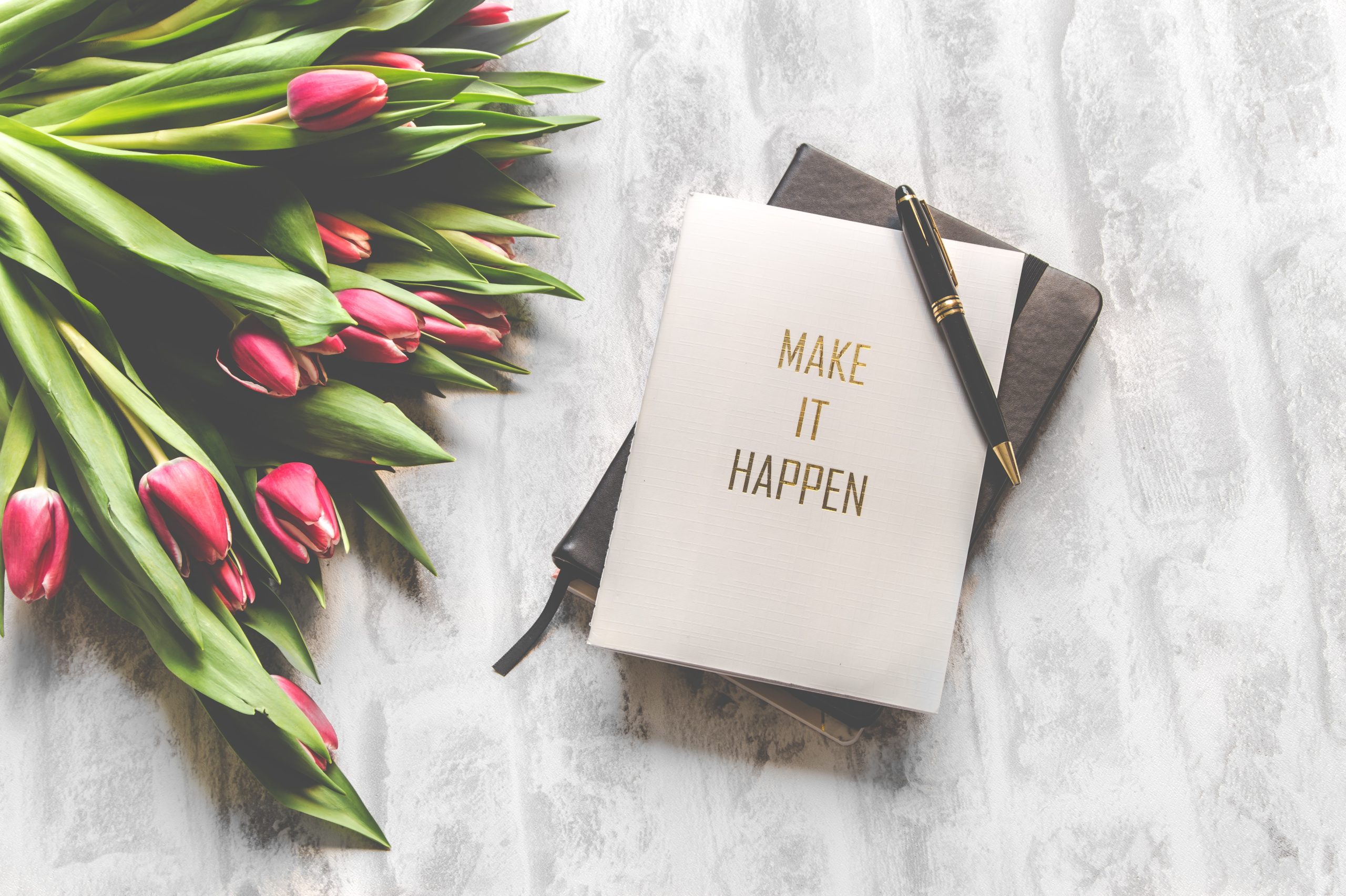 make it happen notebook for 10 life tips next to bundle of roses