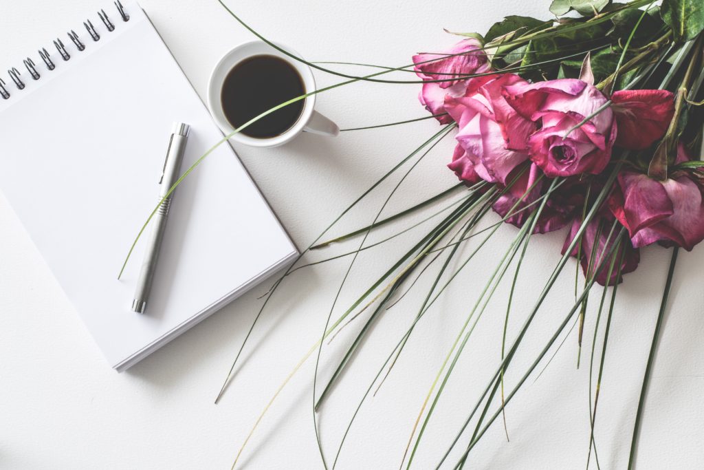 white notepad for 10 life tips next to cup of coffee and bouquet of roses